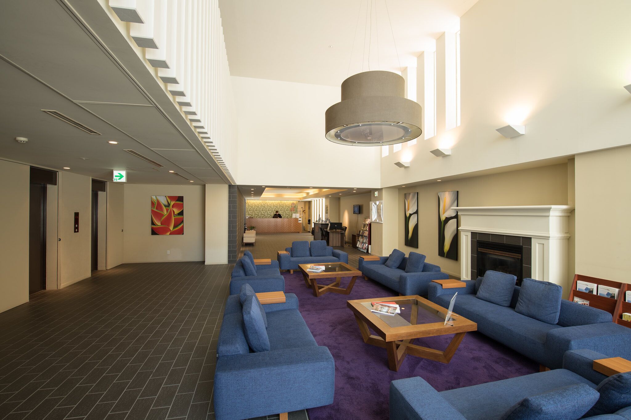 A lobby with sofas, coffee tables, a fireplace, and a staircase.