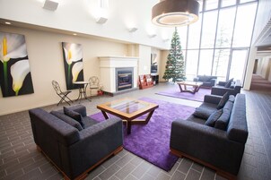 Un salon spacieux avec une cheminée, des fauteuils confortables et un sapin de Noël.