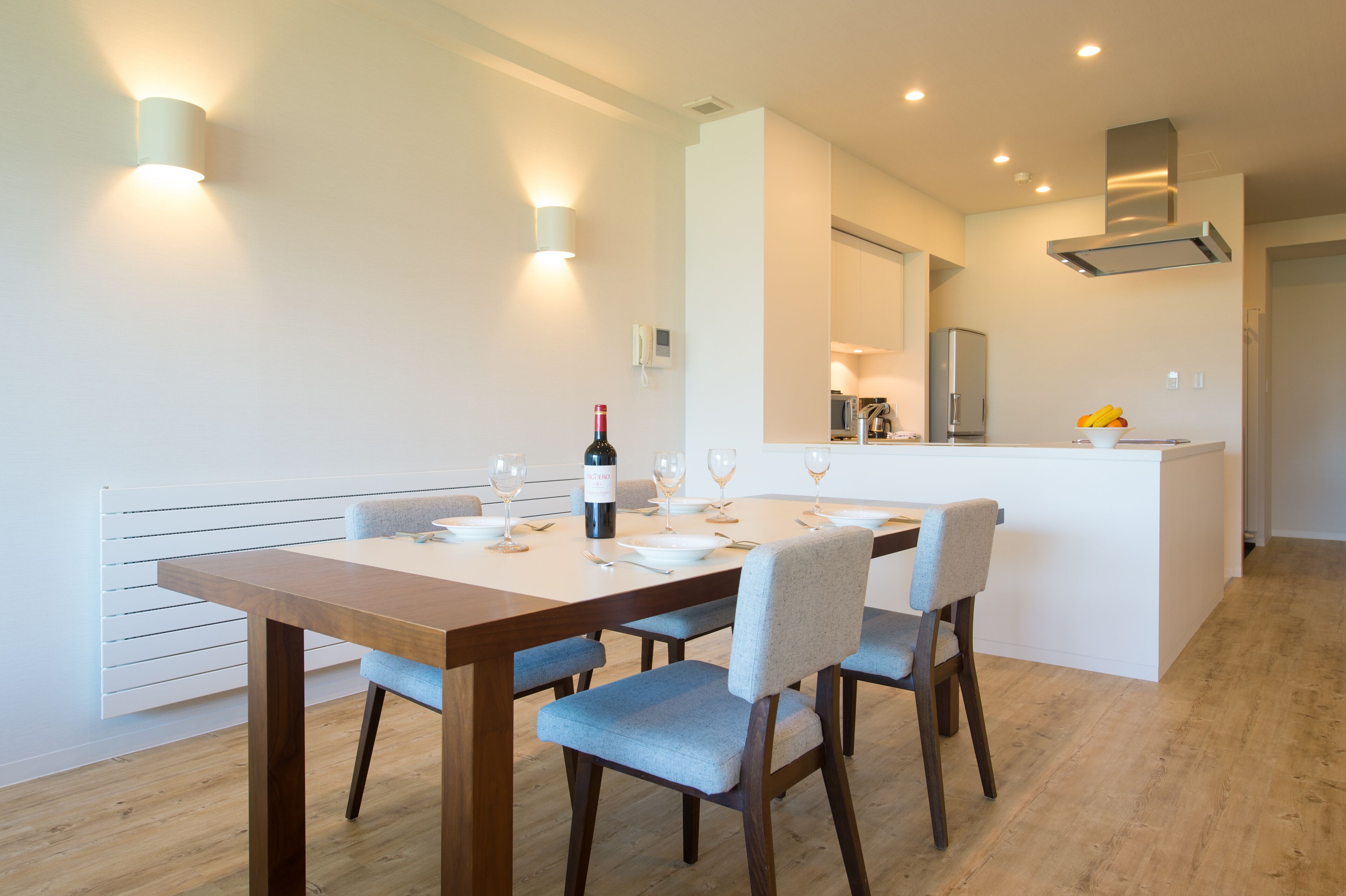 A dining area with a wooden table, blue upholstered chairs, and a wine bottle.