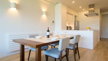 A dining area with a wooden table, blue upholstered chairs, and a wine bottle.