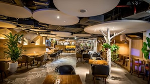 A modern restaurant with high ceilings, pendant lighting, and a variety of seating arrangements. - Dream Hotel & Apartment (Hanoi)