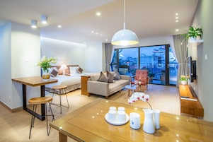 Quarto de hotel moderno com uma janela grande, área de refeições, sofá e escrivaninha.