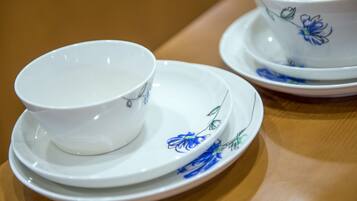 A set of white porcelain tea cups and saucers with blue floral designs, placed on a wooden table.