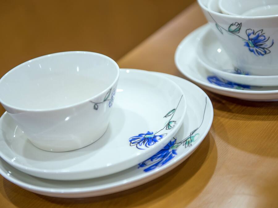 A set of white porcelain tea cups and saucers with blue floral designs, placed on a wooden table.