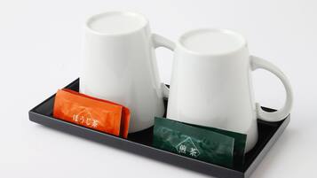 Dos tazas de cerámica blanca sobre una bandeja con dos bolsitas de té, una naranja y una verde.