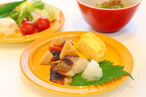 A table with two plates of food, one with grilled meat and vegetables, and another with rice and a leaf garnish. - Quad Inn Yokote (Yokote)