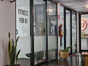 L’entrée d’une salle de sport, avec des portes en verre, un panneau d’accueil et un panneau indiquant que l’accès est réservé aux clients.