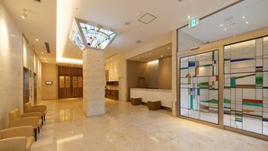 Um hall amplo com teto alto, balcão de recepção e área de estar com cadeiras.