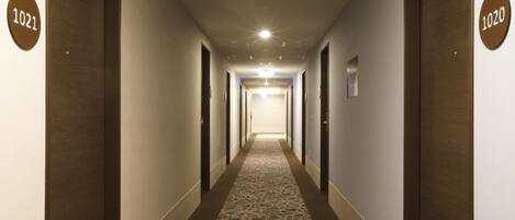 A hotel hallway with doors numbered 1021 and 1020, carpeted floor, and recessed lighting.