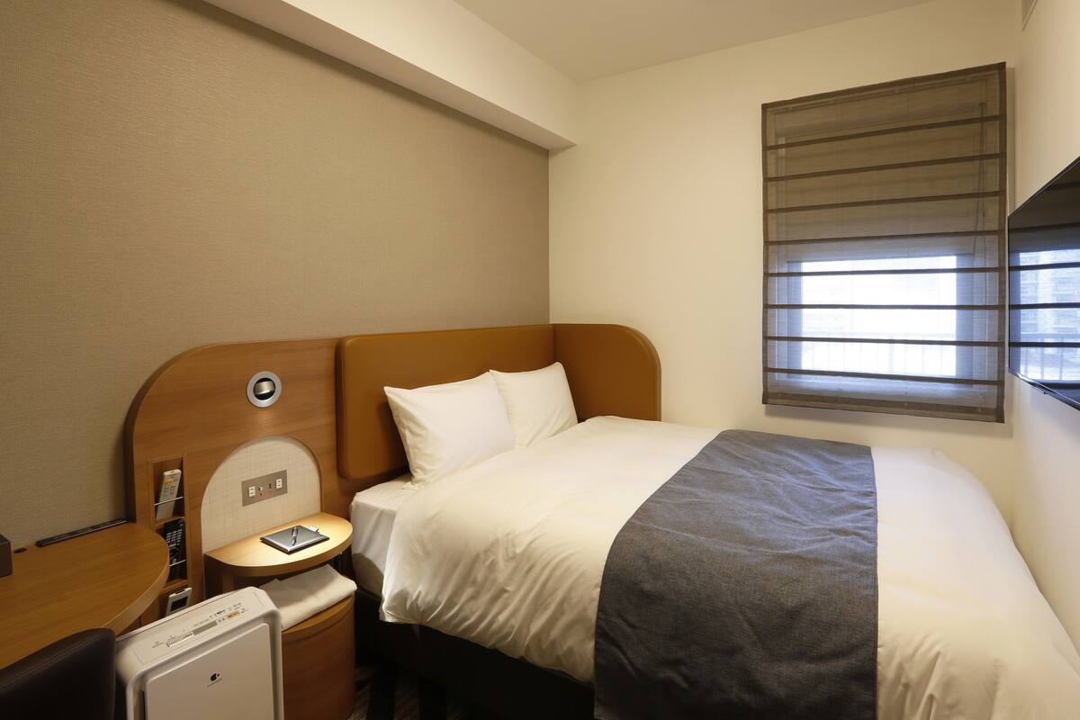 Ein Hotelzimmer mit einem Bett, einem Nachttisch und einem kleinen Schreibtisch mit Stuhl.