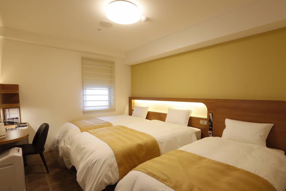 Ein Hotelzimmer mit zwei Betten, einem Schreibtisch und einem Stuhl.