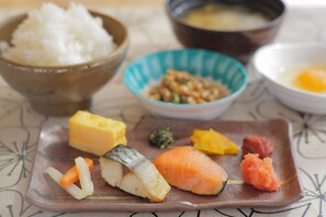 A plate with various sushi pieces, a bowl of rice, and a bowl of soup.