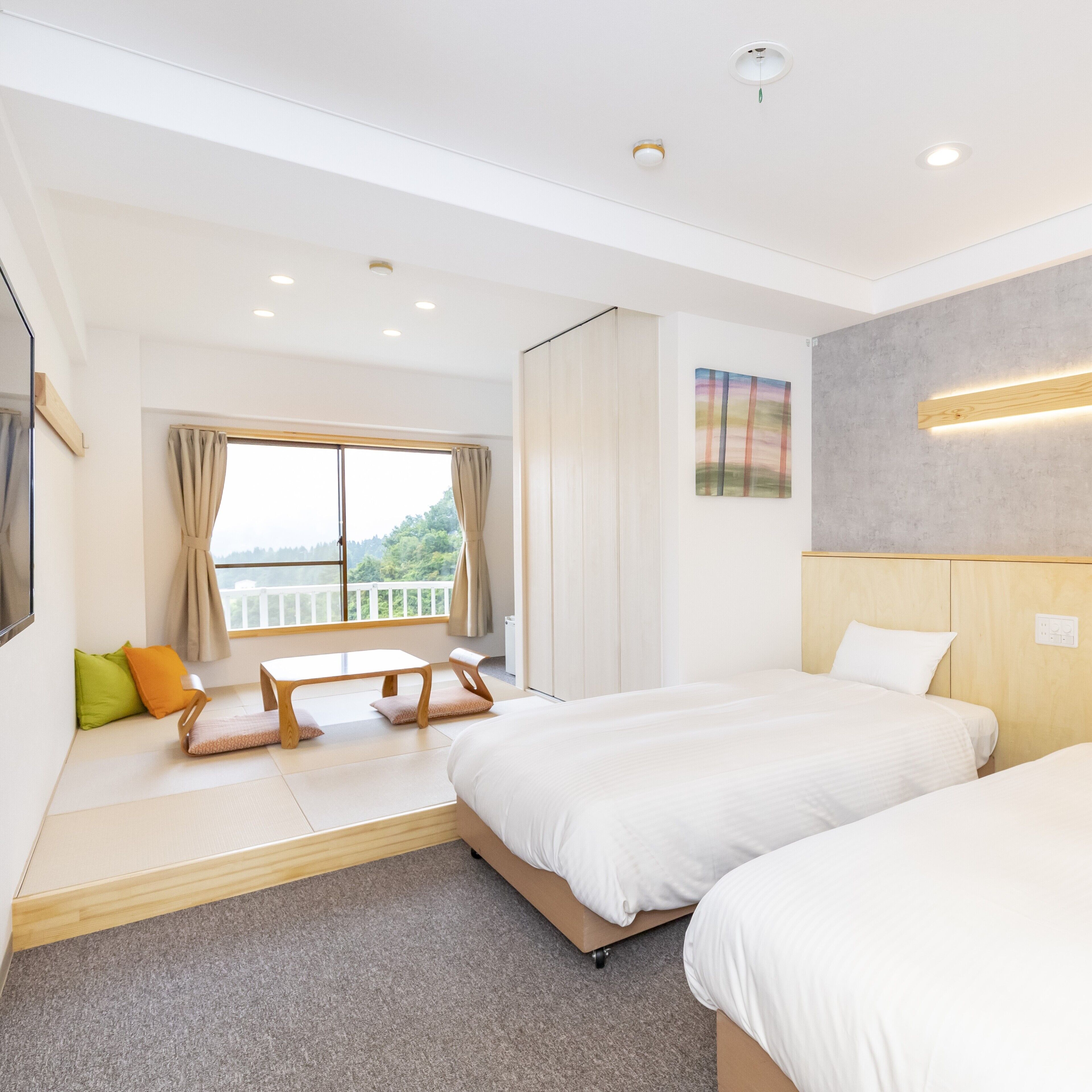 A hotel room with a bed, a sofa, a table, and a window with curtains.