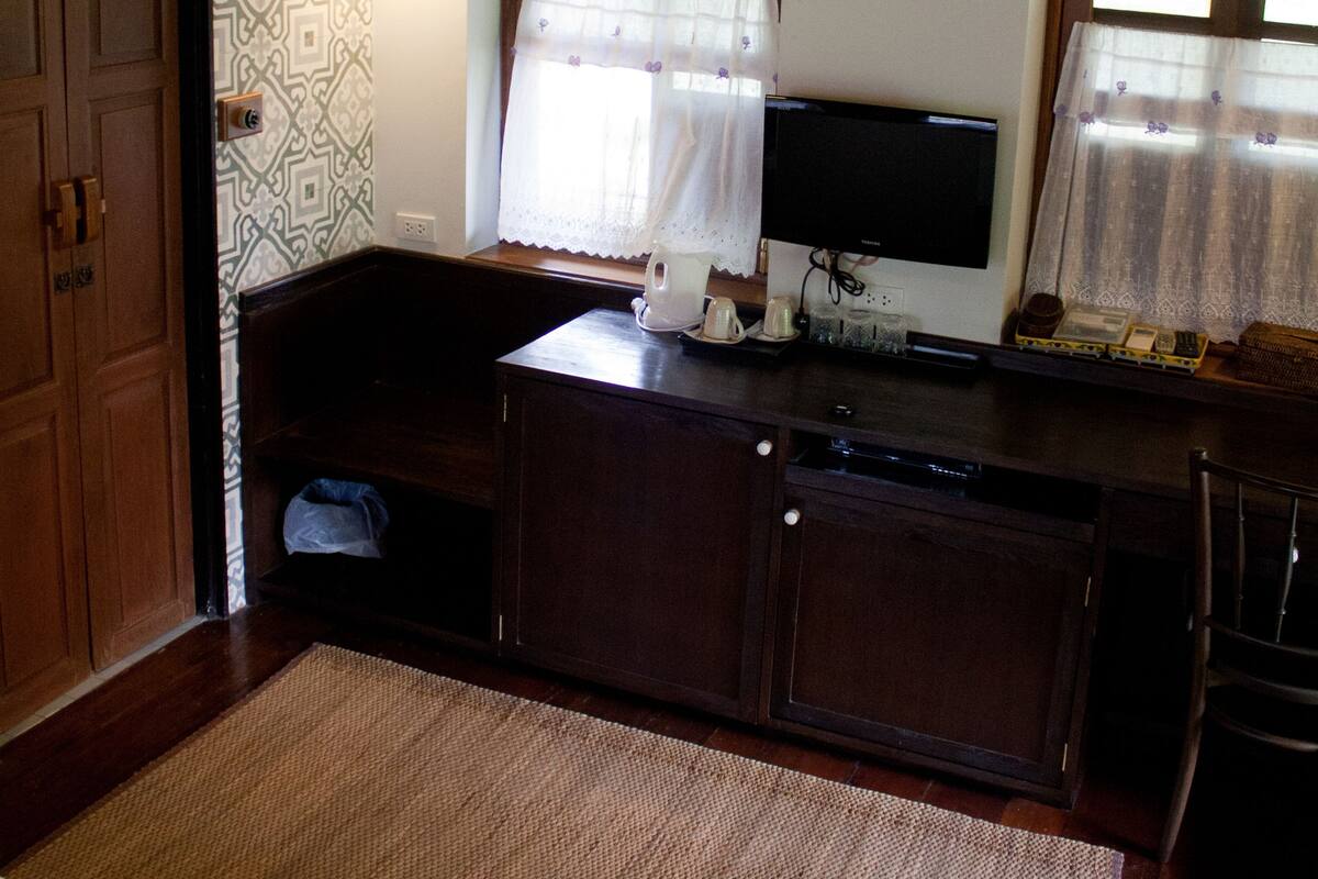 A small kitchen with a microwave, a sink, and a window with curtains.