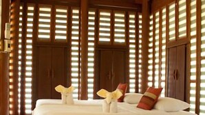 A hotel room with a large bed, wooden walls, and a ceiling fan. - Ayodhara Village (Ayutthaya)