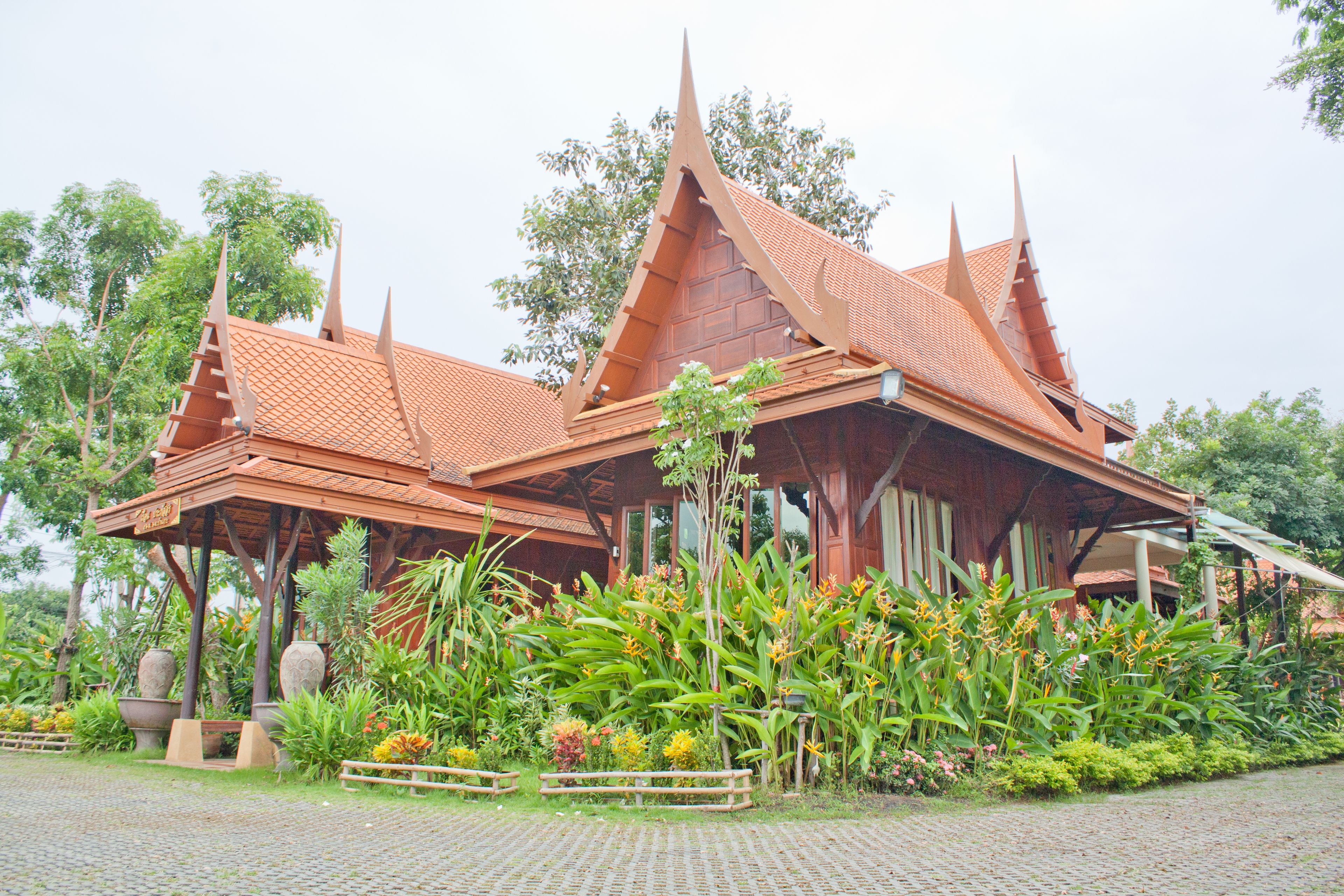 A traditional wooden structure with a tiled roof, surrounded by lush tropical vegetation.