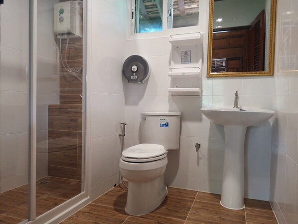 Un baño con inodoro, lavabo y cabina de ducha.