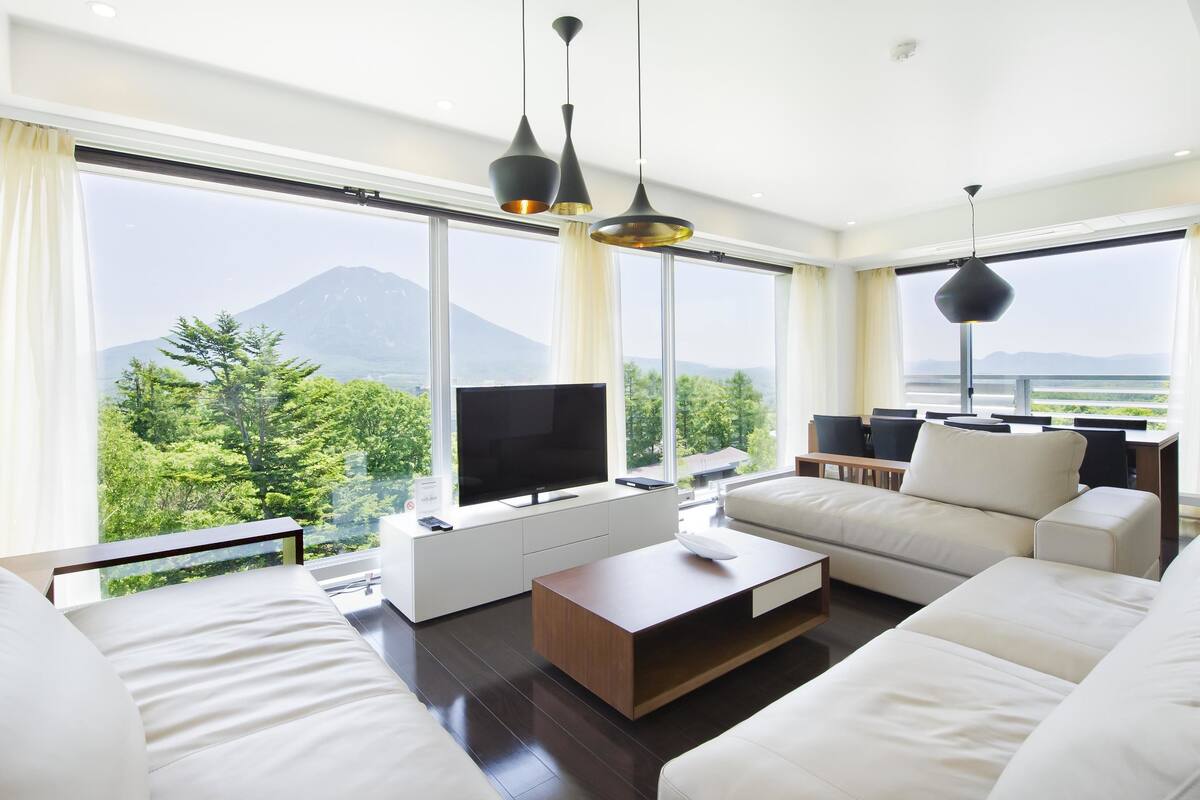A modern living room with a flat-screen TV, a coffee table, and a sofa set.