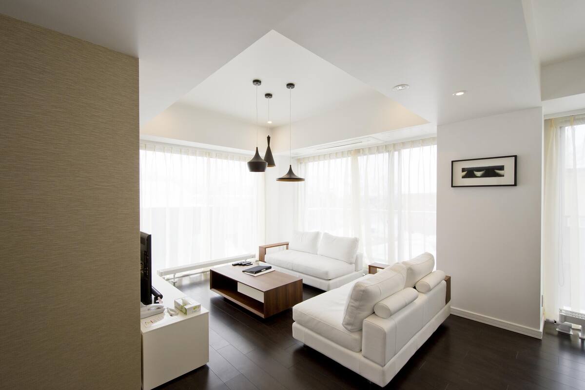 A modern living room with a white sofa, a coffee table, and pendant lighting.