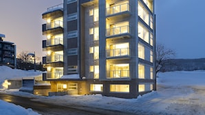 Un edificio de varios pisos con balcones, ventanas iluminadas y un letrero que dice "KIZUNA".