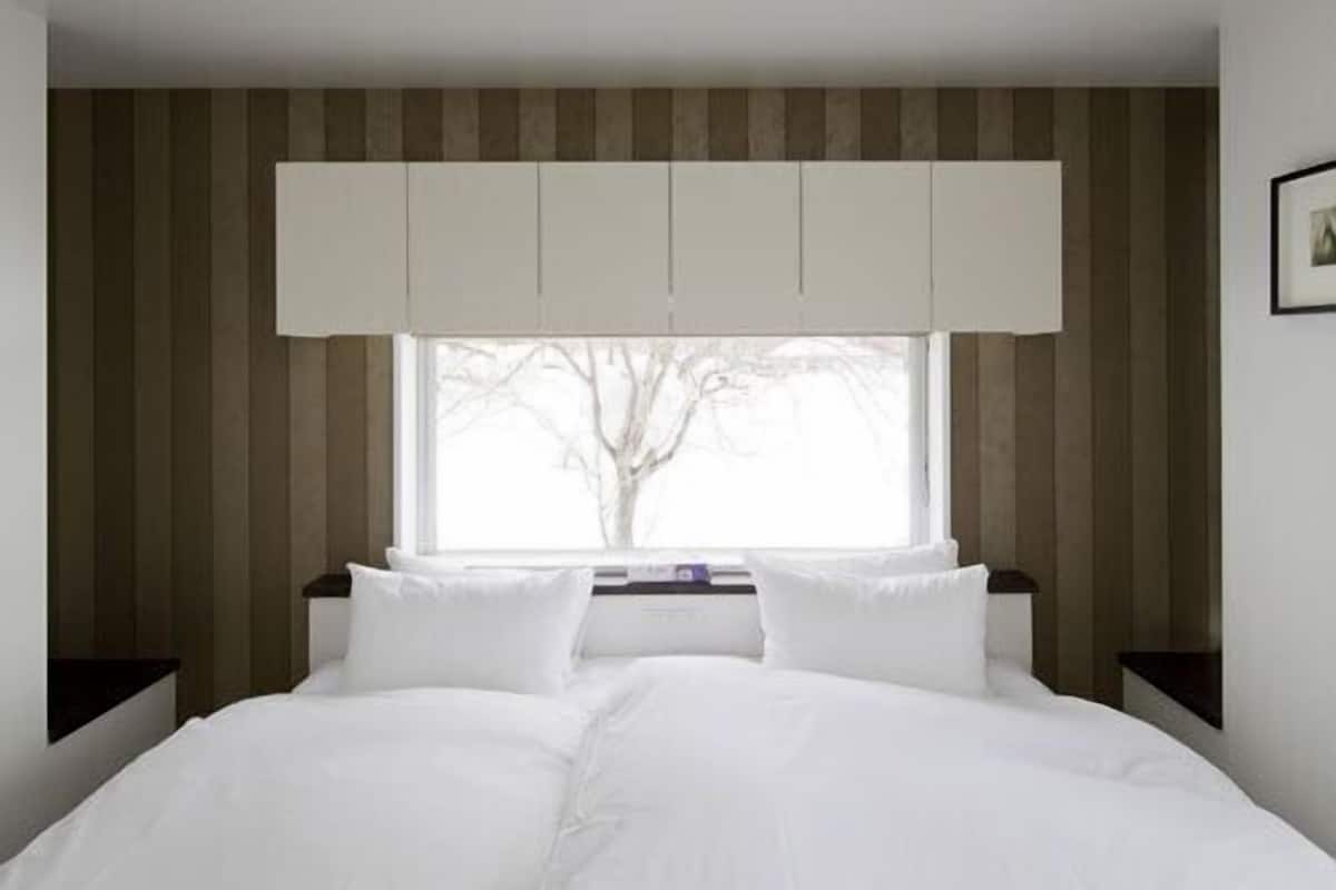 A bedroom with a bed, a window, and a wall-mounted cabinet.
