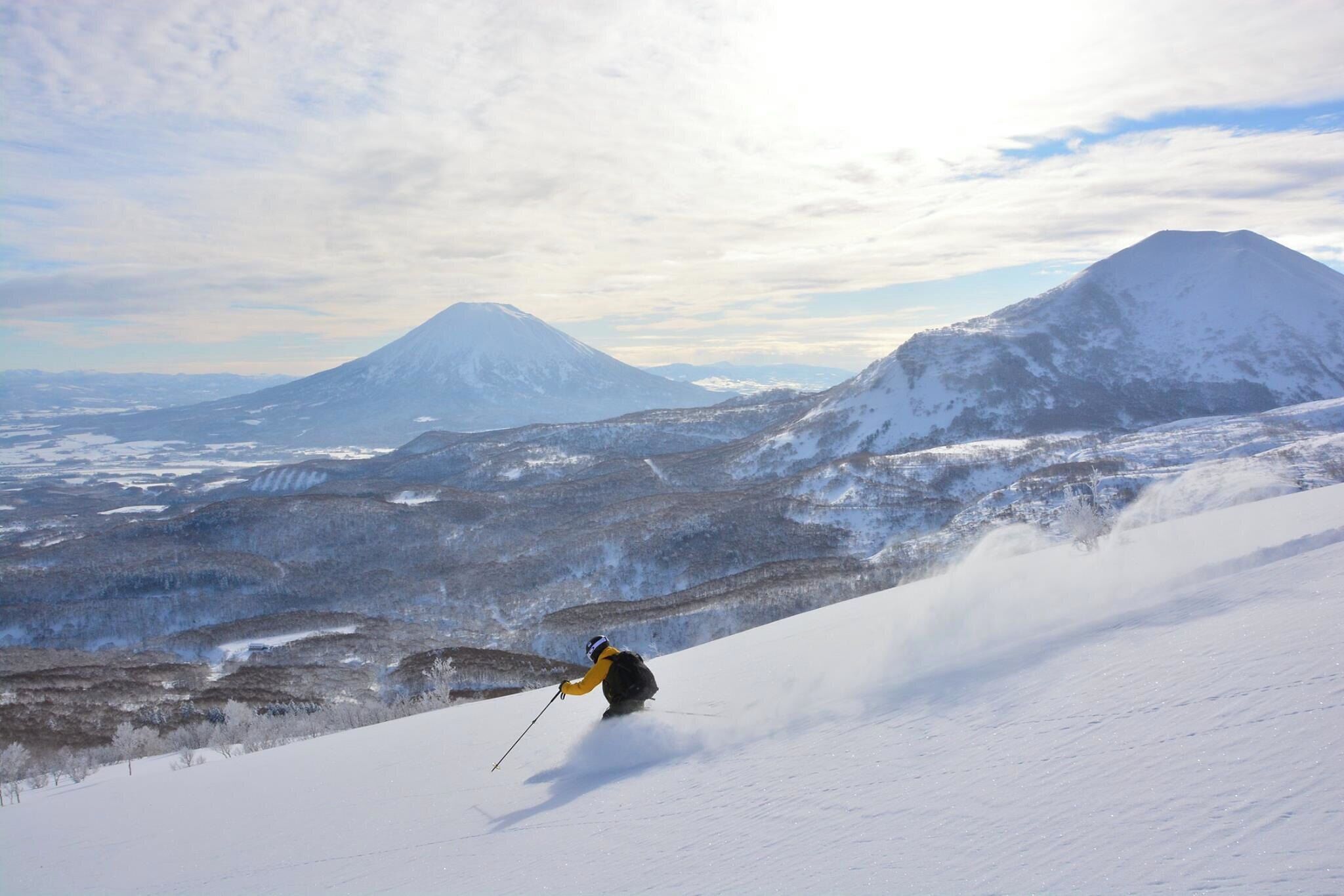 A snowy mountain landscape with a skier in motion.