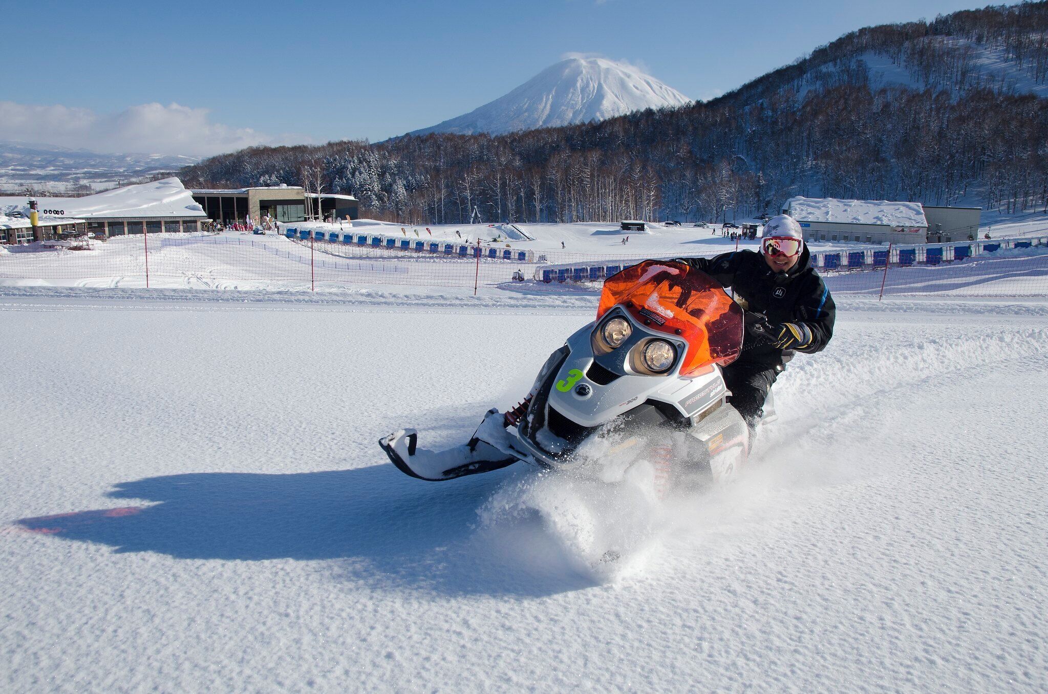 A snowmobile on a snowy surface with a mountainous background.