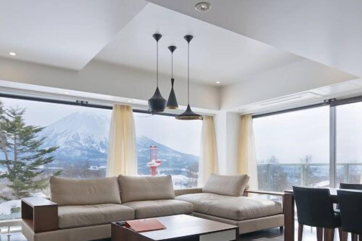 A modern living room with a sectional sofa, a coffee table, and a dining area with chairs.