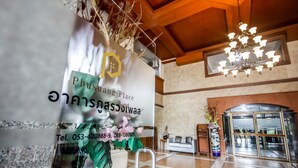 A reception area with a signboard, a chandelier, a reception desk, and a glass door entrance. - Phusuang Place (Chiang Mai)