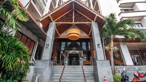 A hotel entrance with a modern design, featuring a staircase leading to the entrance, a large wooden canopy, and a decorative ceiling light. - Phusuang Place (Chiang Mai)