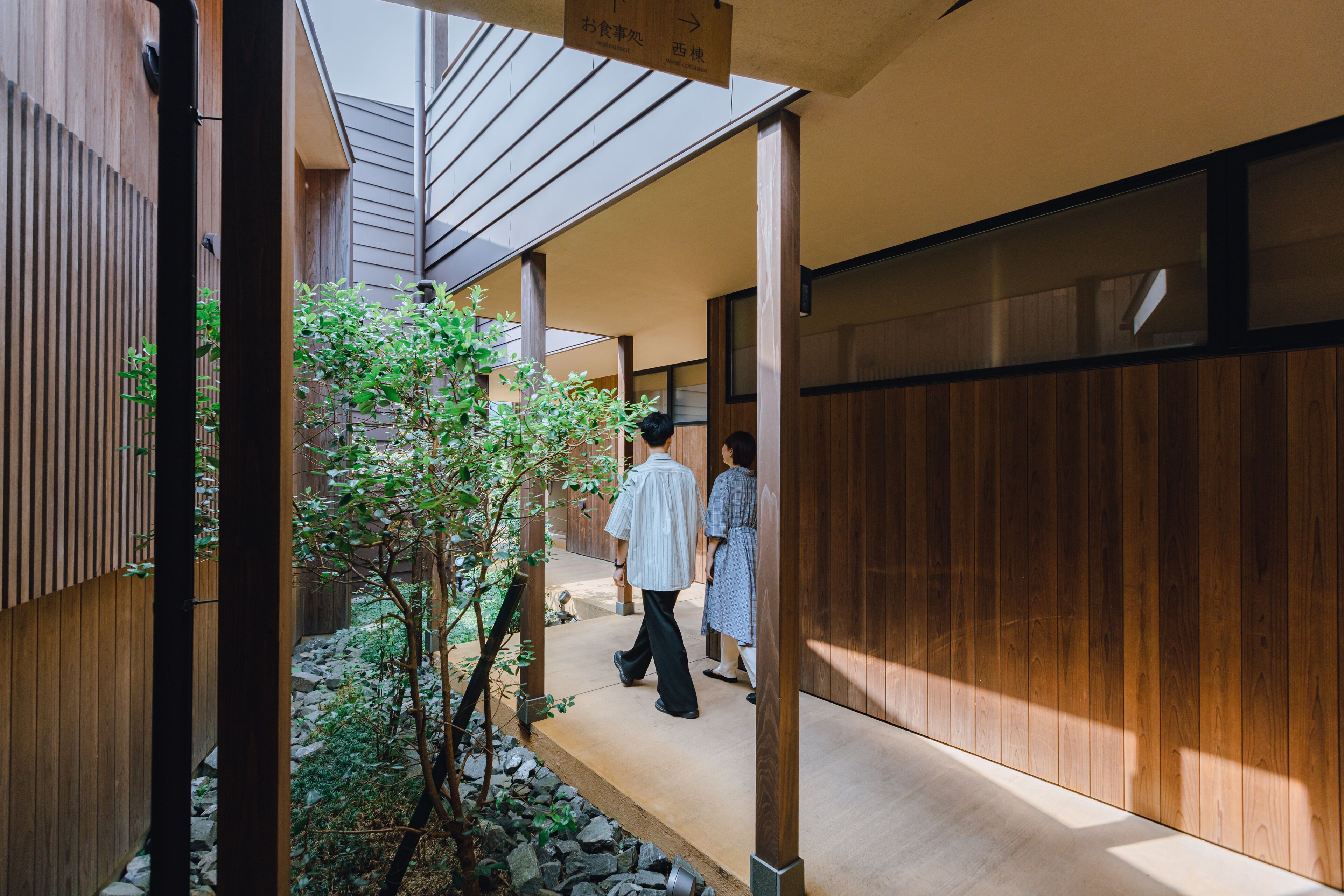 A traditional Japanese-style corridor with wooden walls and a small tree.
