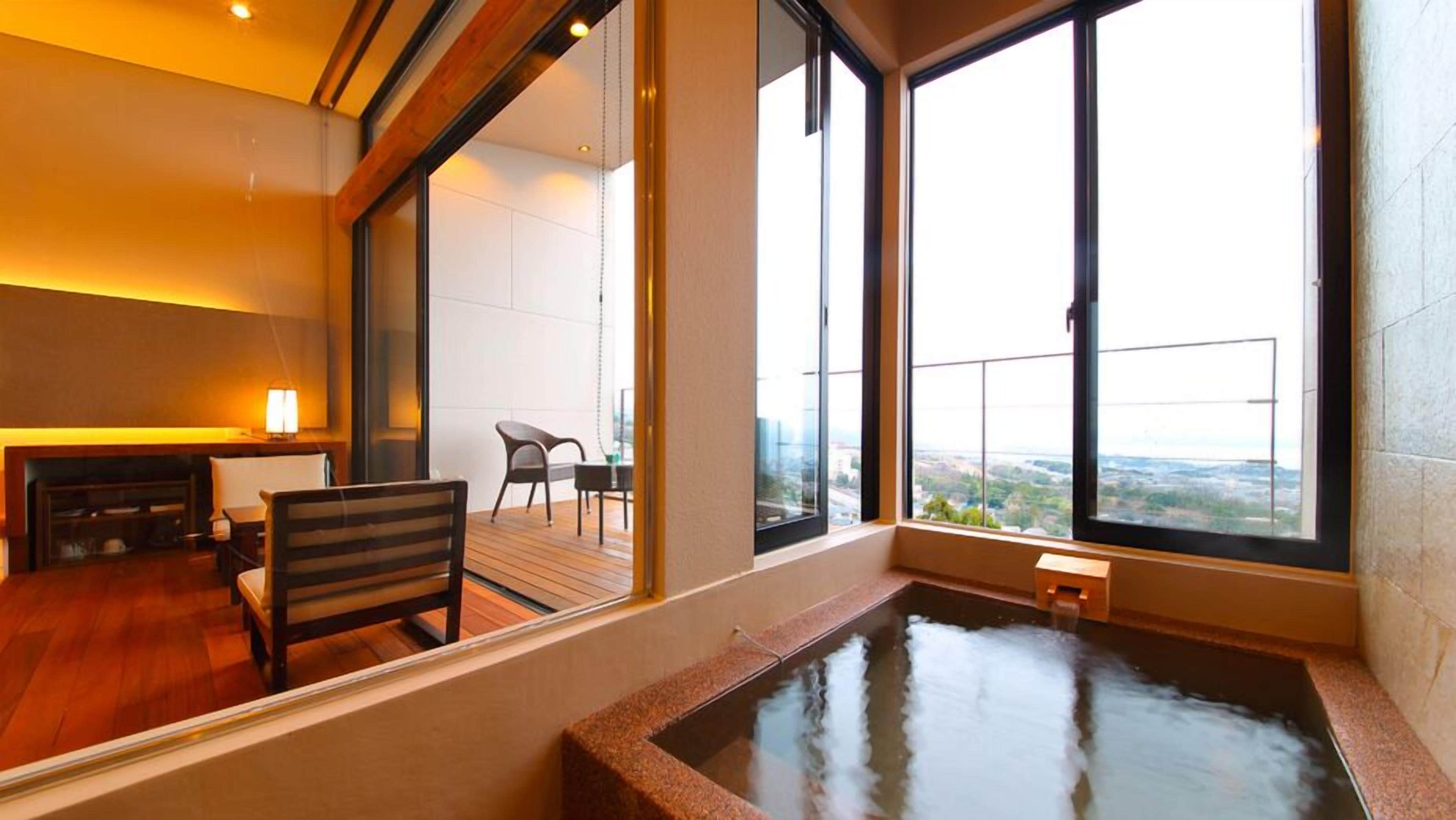 A modern room with a large window, a wooden floor, a small table, and a chair.
