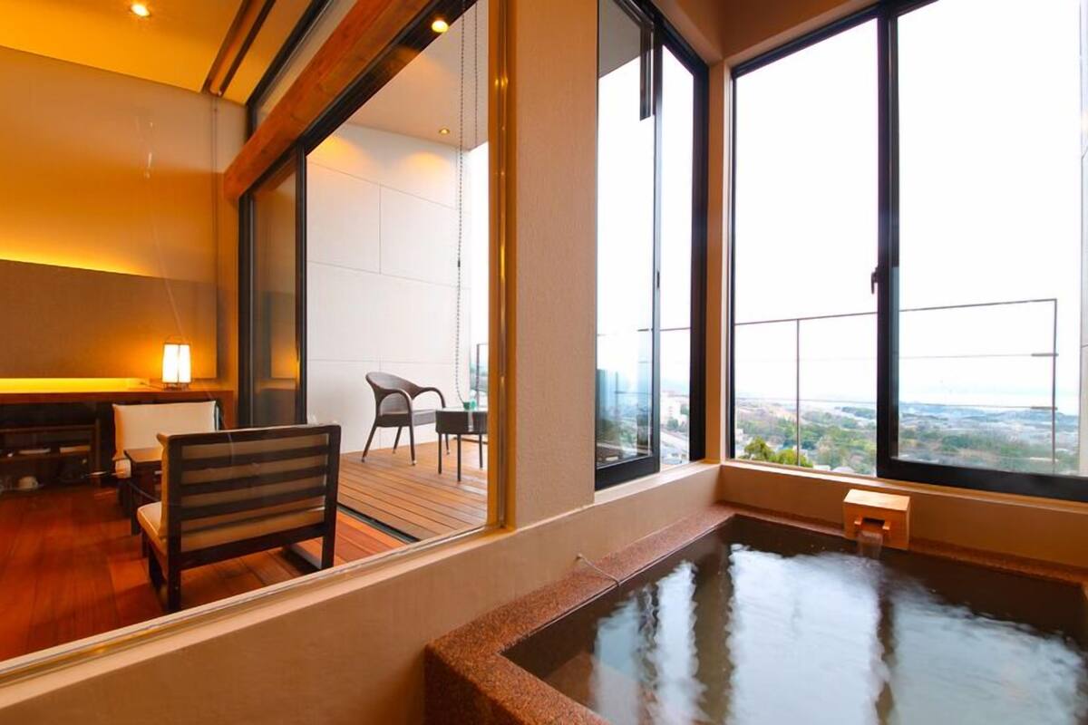 A modern room with a large window, a wooden floor, a small table, and a chair.