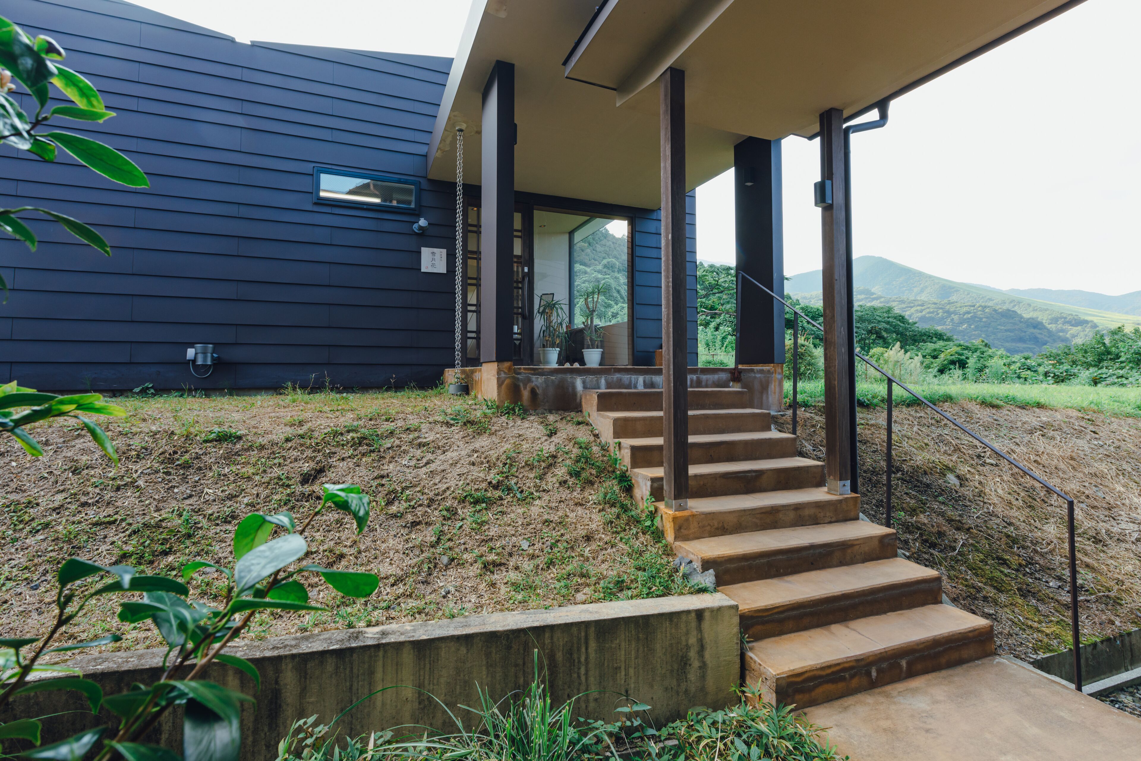 Una casa moderna con una escalera de madera que lleva a un porche cubierto.