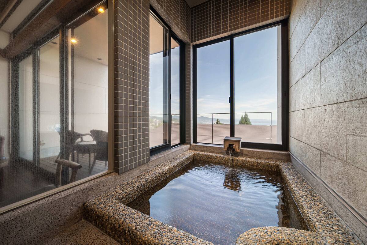 A hot tub with a view of the outdoors, a seating area, and a small table.