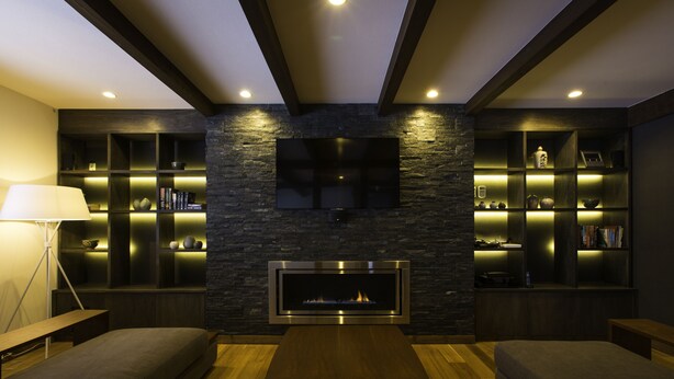 A modern living room with a fireplace, built-in shelves, and a flat-screen TV.