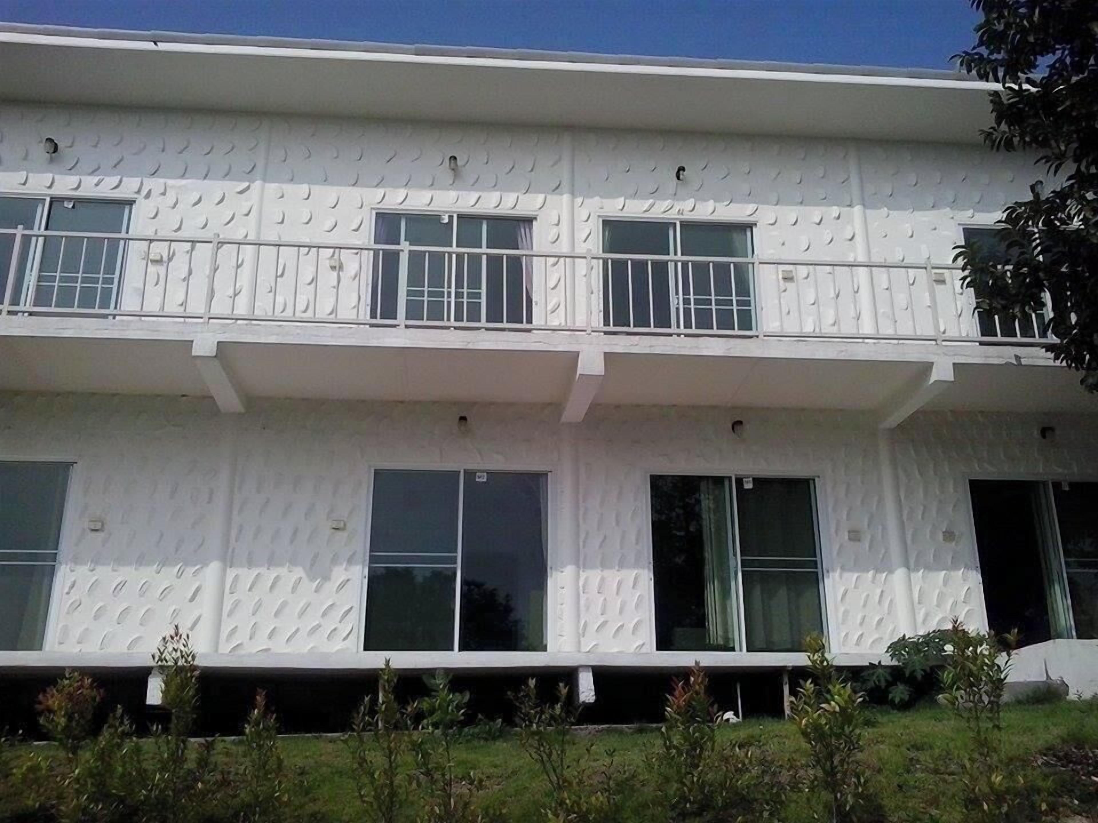 A two-story building with a textured facade, large windows, and a flat roof.
