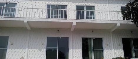 Un edificio de dos pisos con fachada texturizada, ventanas grandes y techo plano.