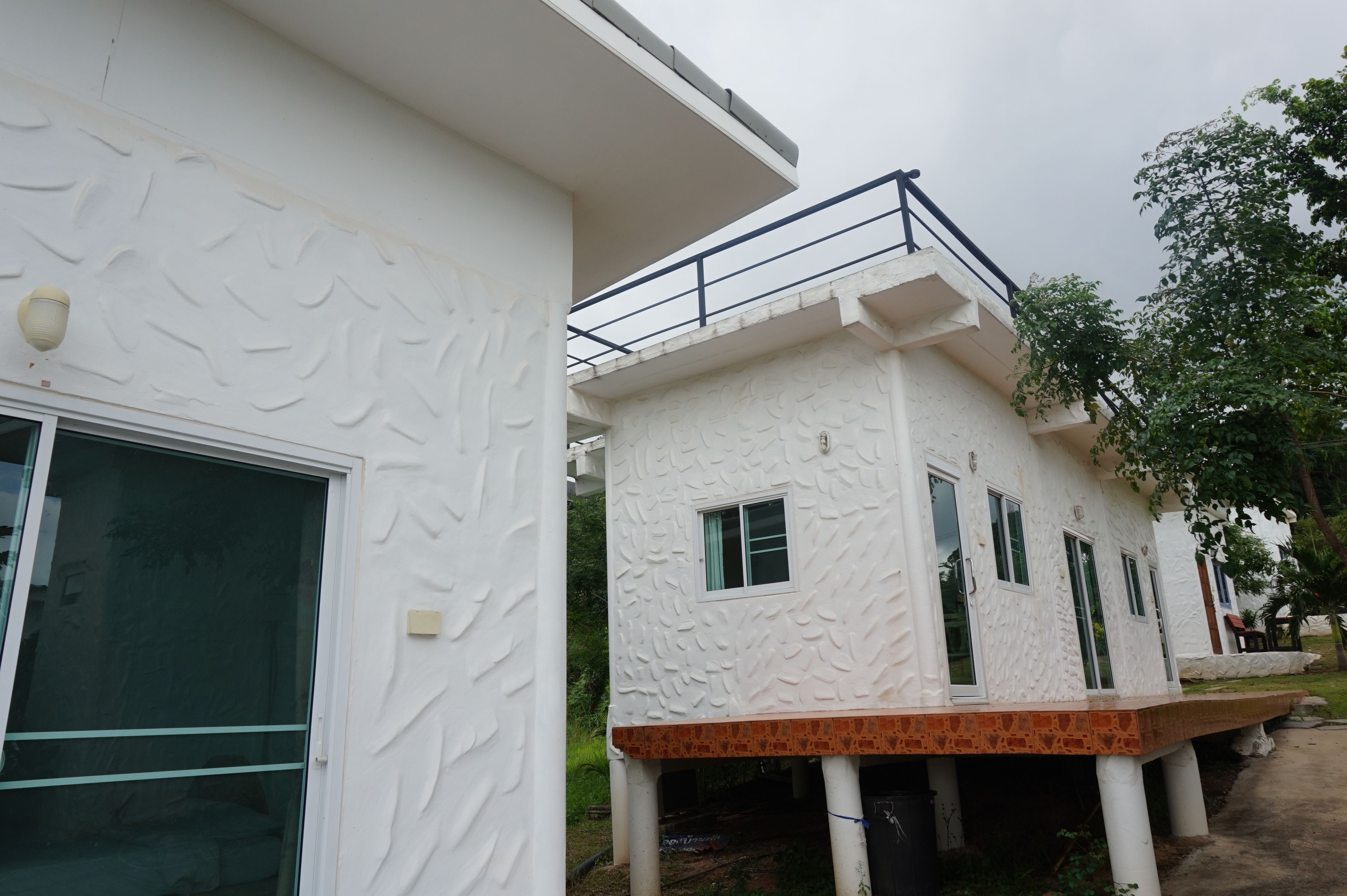 A modern building with a textured facade, a balcony, and a window.