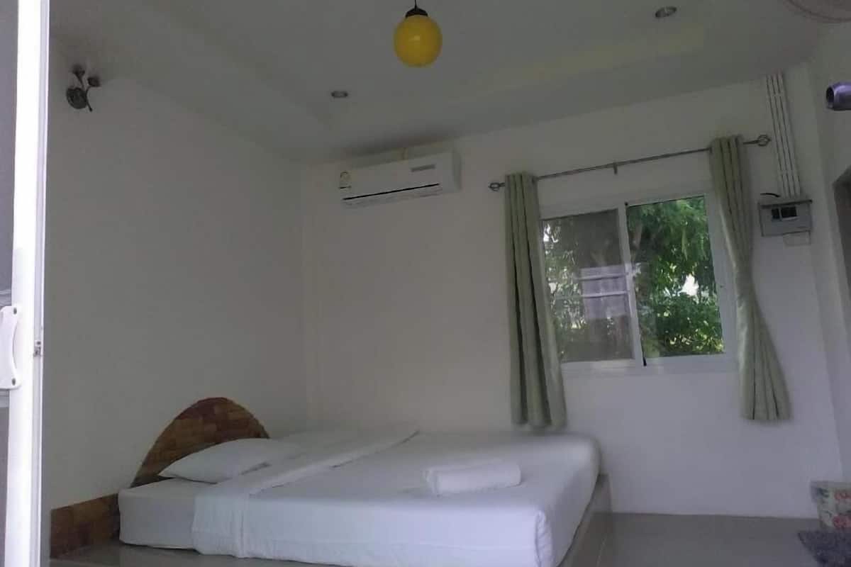 Un dormitorio con cama, aire acondicionado, ventana con cortinas e iluminación colgante.