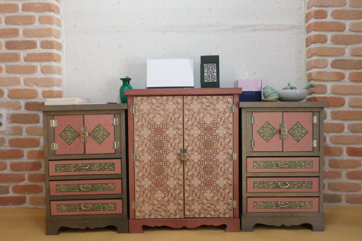 A model room with two wooden cabinets, a small table, and a vase.