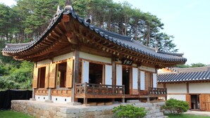 Un edificio tradicional coreano con estructura de madera, base de piedra y tejado de tejas.
