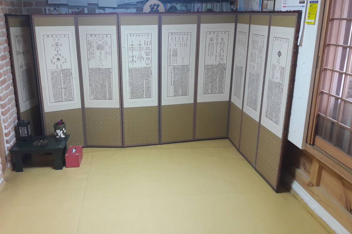 A room with a traditional Japanese shoji screen, a small desk with a lamp, and a red box on the floor.