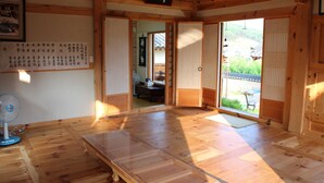 Una habitación japonesa tradicional con suelo de tatami, puertas correderas y vistas a un jardín.
