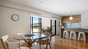 Una cocina moderna con una mesa de vidrio, sillas de madera y una barra con taburetes.