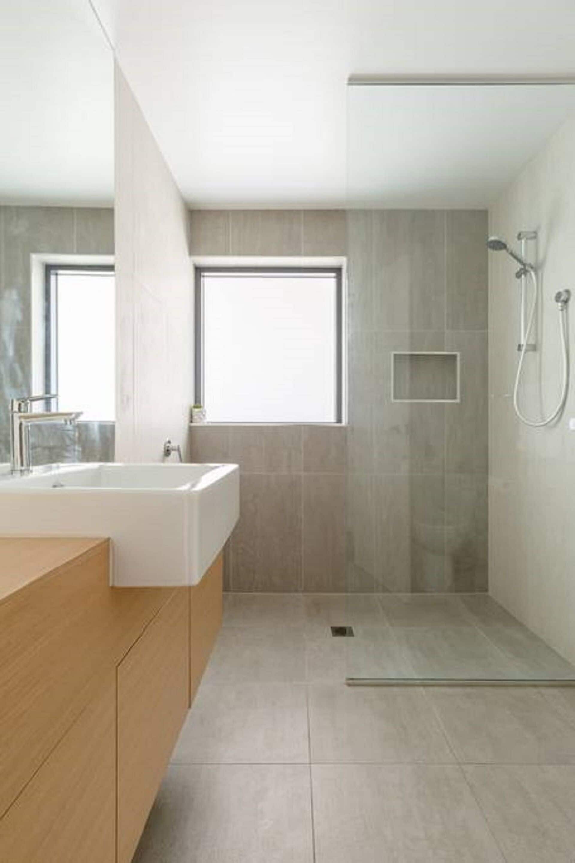 Un bagno moderno con una doccia spaziosa, una finestra e un mobile bagno in legno.