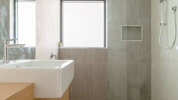Un bagno moderno con una doccia spaziosa, una finestra e un mobile bagno in legno.