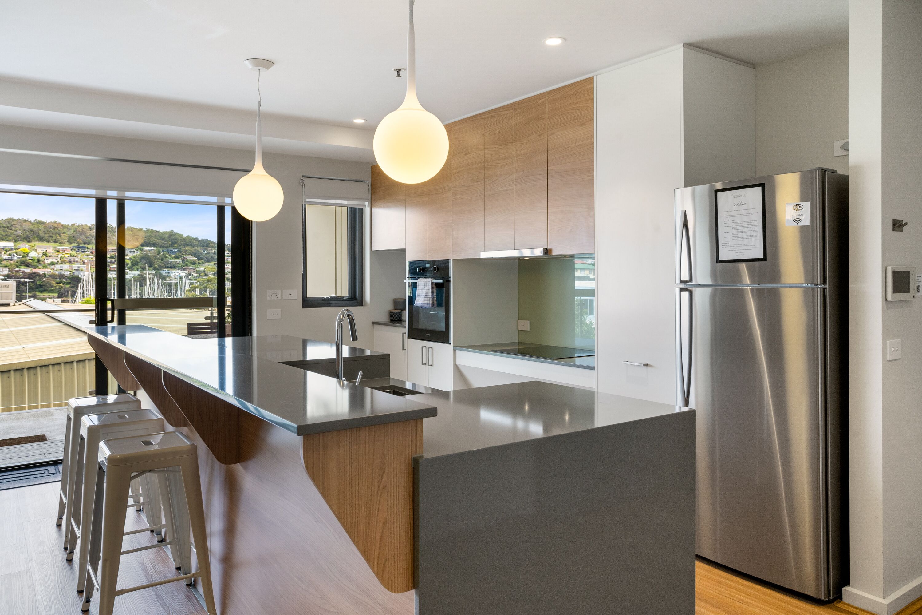 A modern kitchen with a large island, stainless steel appliances, and a view of the city.