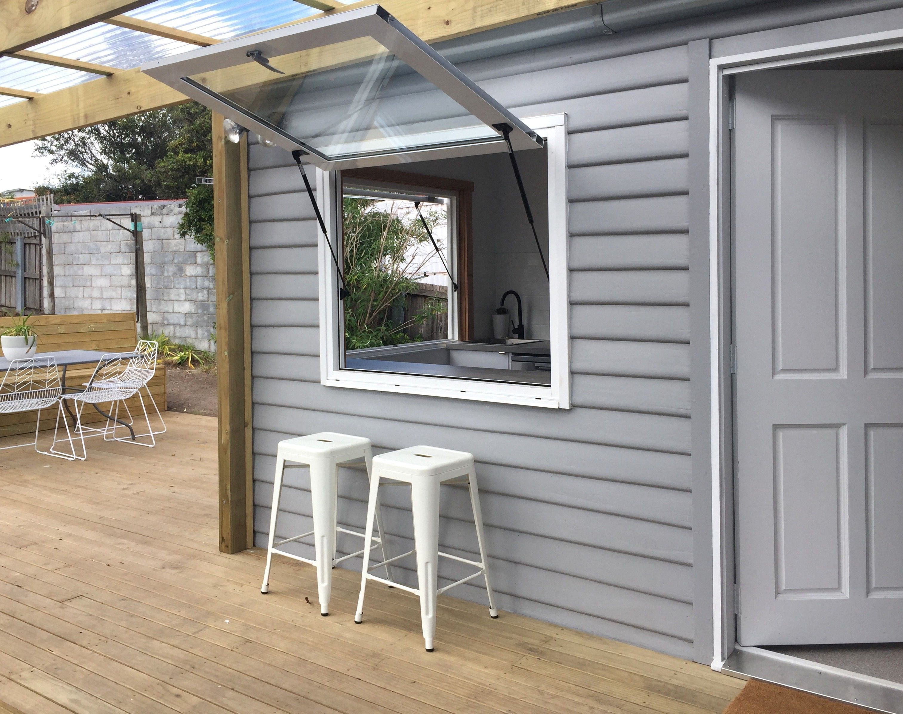 A covered patio with a table and chairs, a window with a view, and a door.