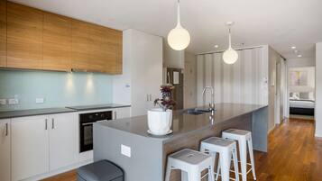 A modern kitchen with a central island, bar stools, and pendant lighting.